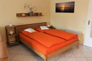 a bedroom with a bed with an orange comforter at Kiebitzstieg 22, Nr5 in Dorum-Neufeld