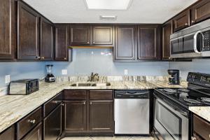 une cuisine avec des armoires en bois et un évier dans l'établissement Phoenix V Vacation Rental Condos, à Orange Beach