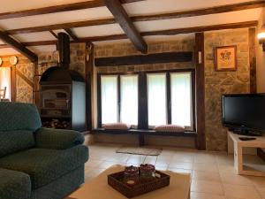 a living room with a couch and a tv at Apartamento Rustico El Cerezo in Lubayo