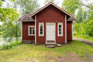 a red house with a white door in the grass at Myllytupa in Merikaarto