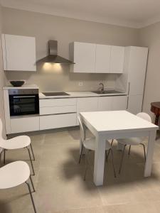 a kitchen with white cabinets and a white table and chairs at Il Cortile di Mabe in Mazara del Vallo