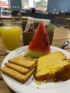 a plate with a slice of watermelon and bread and a drink at Hotel Jardins in Porto Velho