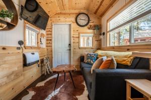 a living room with a couch and a clock on the wall at Glamping Under the Stars Firepit, BBQ & Views in Woodland Park
