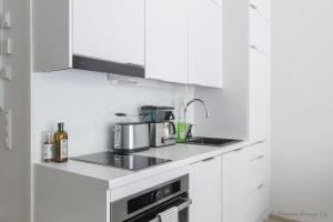 a kitchen with white cabinets and a stove top oven at Pramea Apartments Holvi in Kuopio