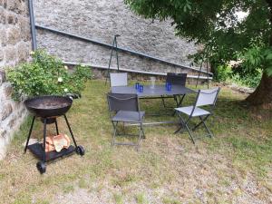a table and chairs and a grill in a yard at Gîte Gîtes de France 4/6 personnes à la Vialatte in Saint-Symphorien +4 photos