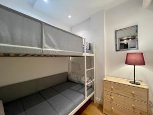 a bedroom with a bunk bed with a lamp and a dresser at Homency - Résidence de l'Alpe 23 in L'Alpe-d'Huez