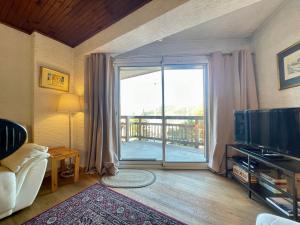 a living room with a large sliding glass door at Homency - Résidence de l'Alpe 23 in L'Alpe-d'Huez