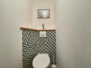 a bathroom with a toilet with a black and white tile wall at Homency - Résidence de l'Alpe 23 in L'Alpe-d'Huez +10 photos