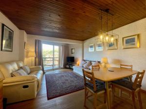 a living room with a table and a couch and a dining room at Homency - Résidence de l'Alpe 23 in L'Alpe-d'Huez