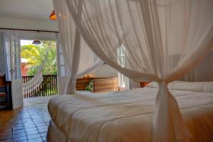 a bedroom with a bed with curtains and a balcony at Hotel Espelho D'Água Arraial e Beach Club in Arraial d'Ajuda +128 photos