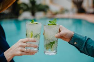 two people holding drinks with a pool in the background at Vale d'El Rei Hotel & Villas in Carvoeiro