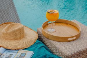 a straw hat and a drink on a table next to a pool at Vale d'El Rei Hotel & Villas in Carvoeiro