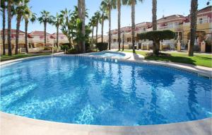 duży basen z palmami przed budynkiem w obiekcie Stunning Home In Orihuela Costa w mieście Playas de Orihuela