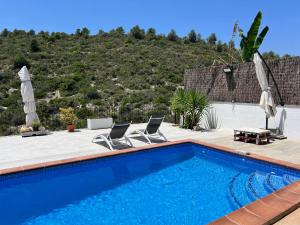 a swimming pool with two chairs and umbrellas at Estudio nuevo zen in Calafell