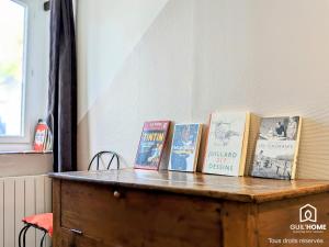 a bunch of books sitting on top of a wooden chest at Le Spacieux - Vue Loire - Queen Size - Free Parking in Orléans