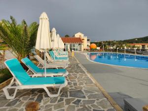 a row of lounge chairs and umbrellas next to a swimming pool at Sea & sun view in Agios Stefanos