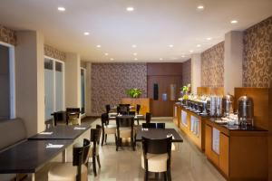 a restaurant with tables and chairs and a bar at Aveon Express Hotel by Daphna International in Yogyakarta