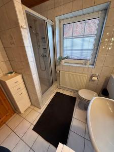 a bathroom with a shower and a toilet and a sink at Strandhaus Nina - Ferienhaus Hooksiel in Hooksiel