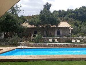 een villa met een zwembad en een huis bij La Baia Guest House in Karítsa