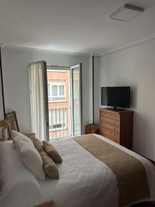 a bedroom with a bed with a television and a window at Vivienda vacacional: Los Abuelos in San Vicente de la Barquera +7 photos