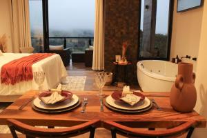 a room with a table and a bath tub and a bed at Chalés Vale da Mantiqueira- chalé 2 in Bueno Brandão +11 photos