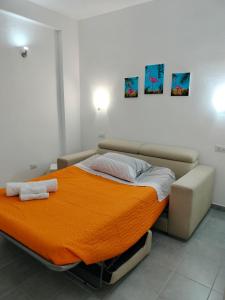 a bed with an orange blanket in a room at Mito apartment in Cagliari