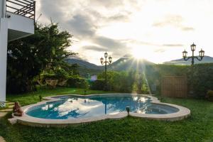 a pool in the yard with the sun in the background at Hotel Juayua in Juayúa