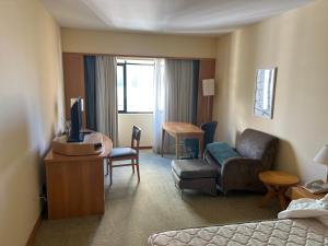 a hotel room with a bed and a couch and a tv at Sol Alphaville Flat completo lazer cama casal in Barueri