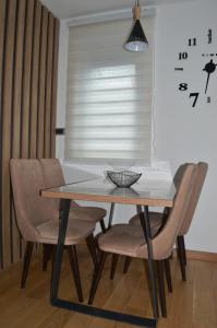 a dining room table with chairs and a clock on the wall at Apartman Ras in Vrnjačka Banja +2 photos