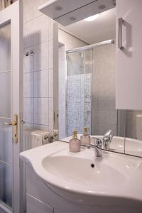 a white bathroom with a sink and a mirror at Apartments Bells of Ljubljana - 3 cosy apartment Private Free Parking in Ljubljana
