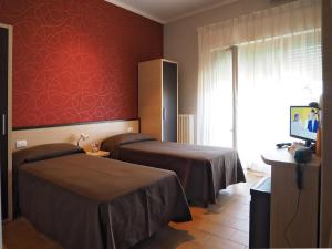 a room with two beds and a red wall at Hotel Velus in Civitanova Marche