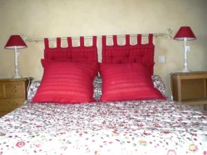 a red bed with two red pillows and two lamps at Gîte Maison Cavalier 2/4 personnes à Gabriac in Gabriac