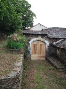 a stone house with a wooden door and flowers at Gîte Maison Cavalier 2/4 personnes à Gabriac in Gabriac
