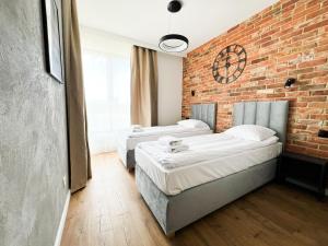 twee bedden in een kamer met een bakstenen muur bij Mint Apartments Gdańsk DOKI in Gdańsk