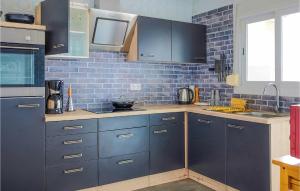 ピネダ・デ・マールにあるNice Apartment In Pineda De Marの青いキャビネットとレンガの壁が備わるキッチン
