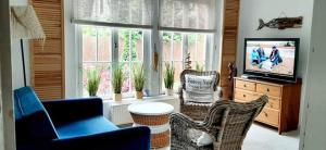 a living room with two chairs and a tv and windows at Dom nad morzem in Pobierowo