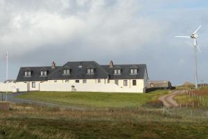 a large white house with a windmill in a field at Decca - Self Catering Shetland in Lerwick