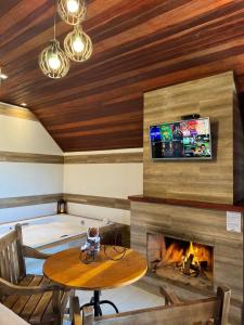 a room with a fireplace and a table and a tv at Pousada Villarejo in Monte Verde
