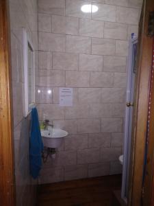 a bathroom with a sink and a white tiled wall at Hostel Villa Nova in Mossel Bay