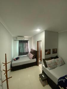 a living room with two beds and a window at Pousada do Maninho in Penha