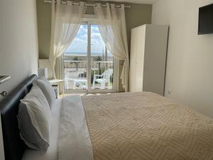 a bedroom with a bed and a large window at Stella di Mare Alojamento Local in Figueira da Foz