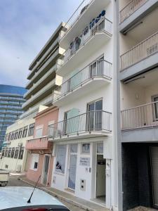 an apartment building with balconies and a car parked in front at Stella di Mare Alojamento Local in Figueira da Foz