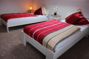 two beds in a bedroom with red and white sheets at Ferienwohnung Seerandweg in Simmerath