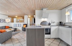 a kitchen with white cabinets and a living room at Stunning Home In Ringkøbing With Sauna in Klegod