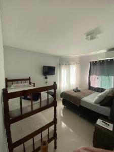 a bedroom with two bunk beds and a television at Pousada do Maninho in Penha
