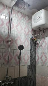 a shower in a bathroom with pink and white tiles at African Taste Guest House. in Kitende