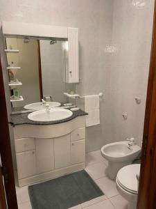 a bathroom with two sinks and a toilet and a mirror at Souto Guimarães Country House in Guimarães