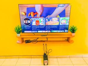 a flat screen tv on a yellow wall with plants at Residence OKEO in Yaoundé