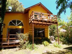 a yellow house with a balcony on top of it at Cabañas Arenas del Faro in Mar del Plata