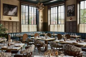 a restaurant with tables and chairs and windows at The Manchester Hotel in Lexington